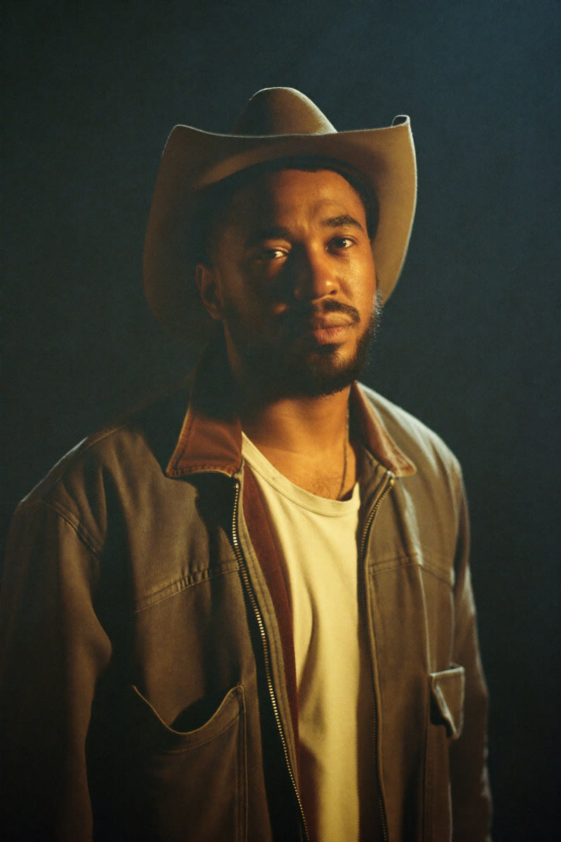 Concept portrait of Dom Thompson, a man in a white cowboy hat and denim jacket, lit by warm golden light